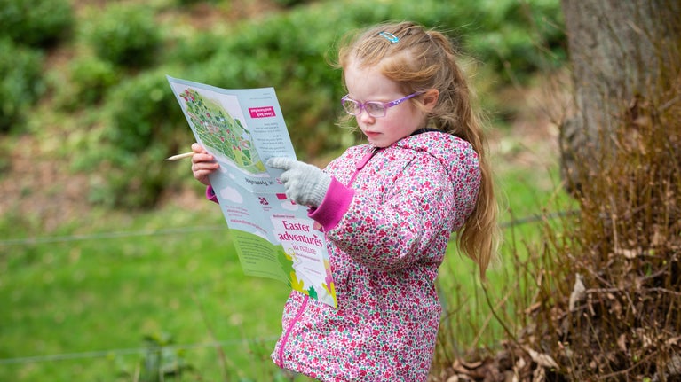 A young girl reads an Easter trail map at Tyntesfield, Somerset